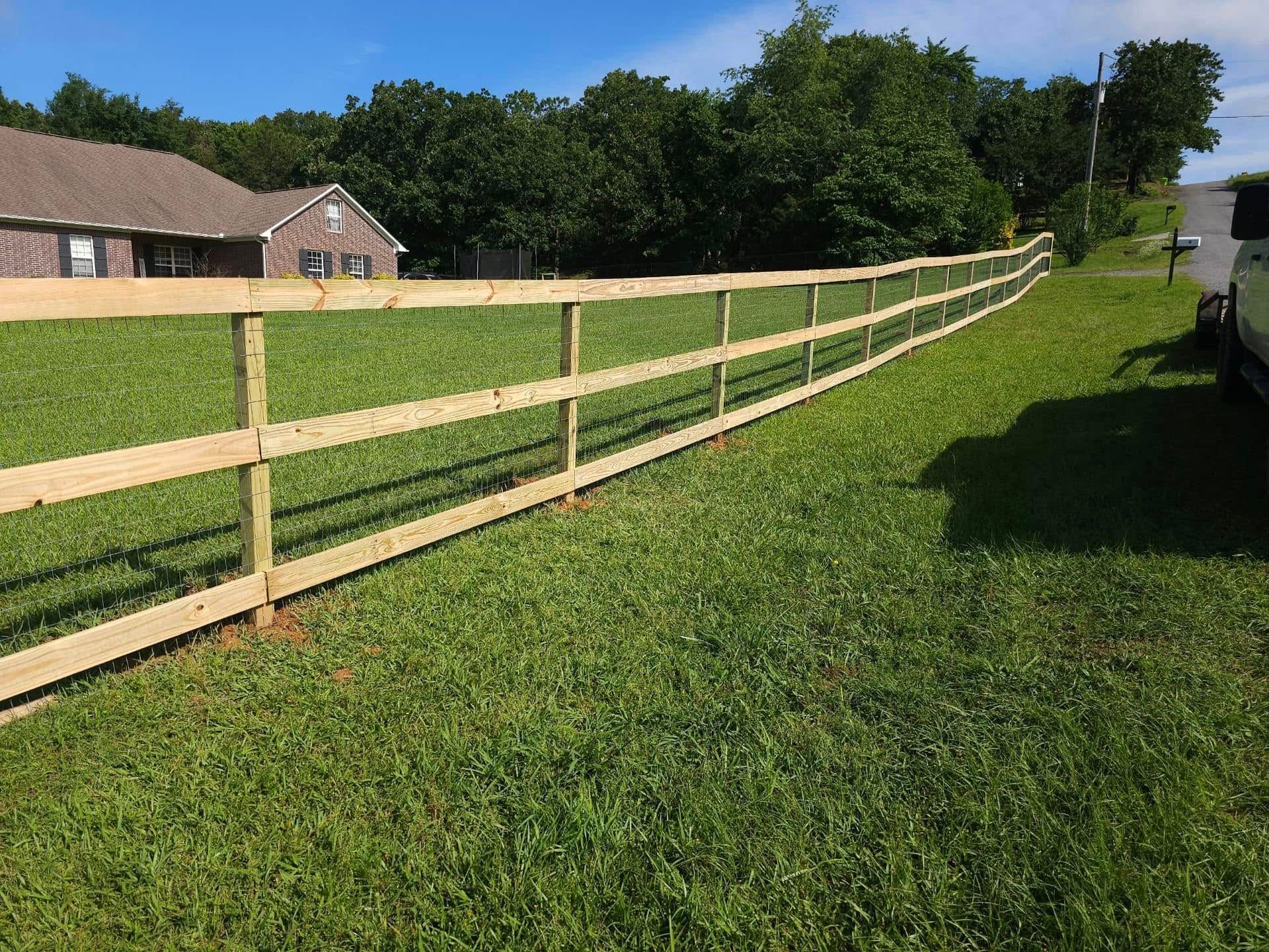 A wooden fence is sitting in the middle of a lush green field.