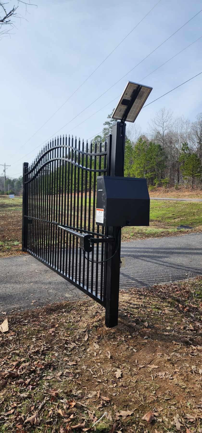 A black gate with a mailbox and a solar panel on top of it.