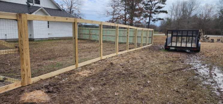 A wooden fence is being built in the backyard of a house.