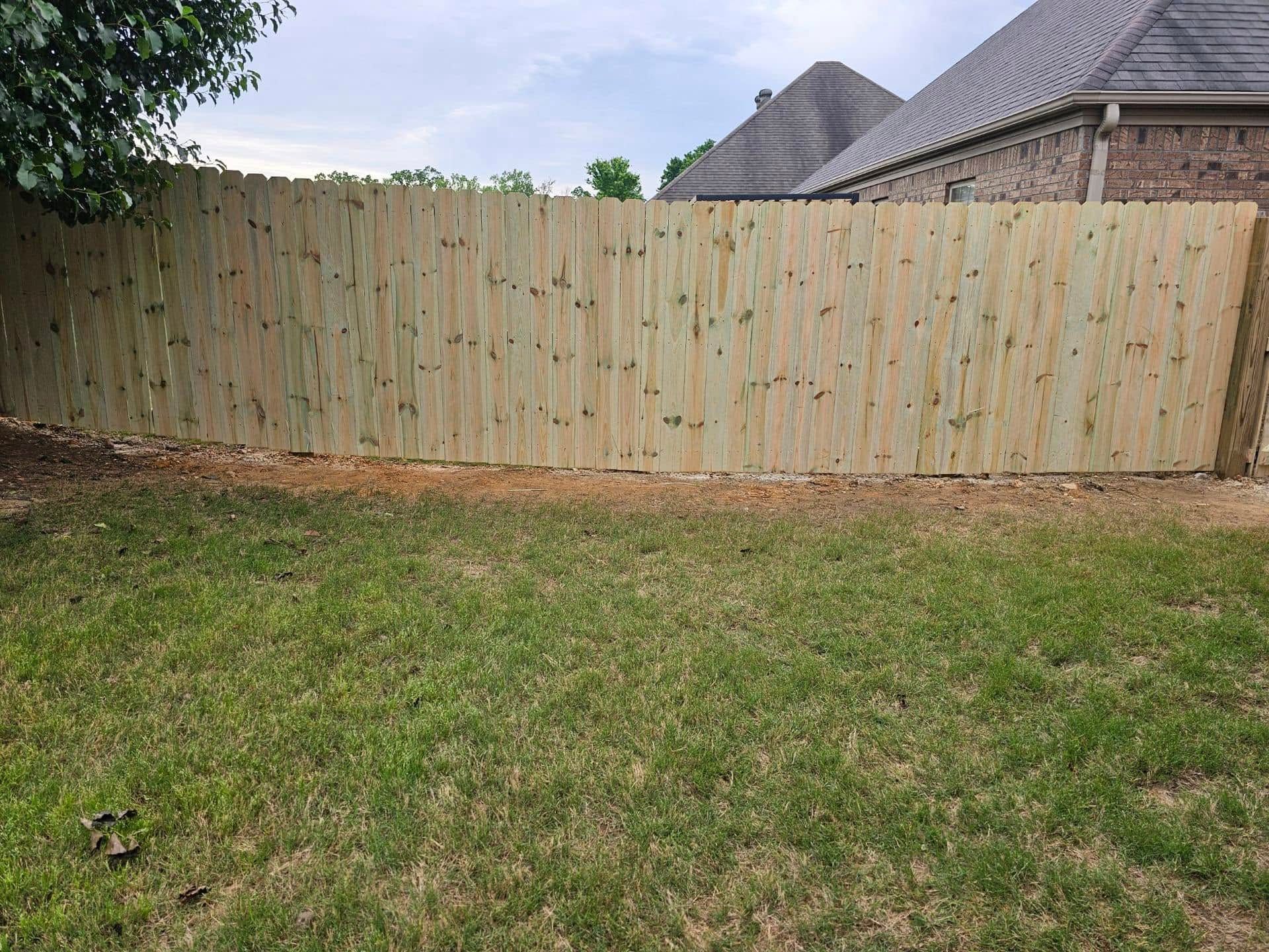 A wooden fence is in the backyard of a house.