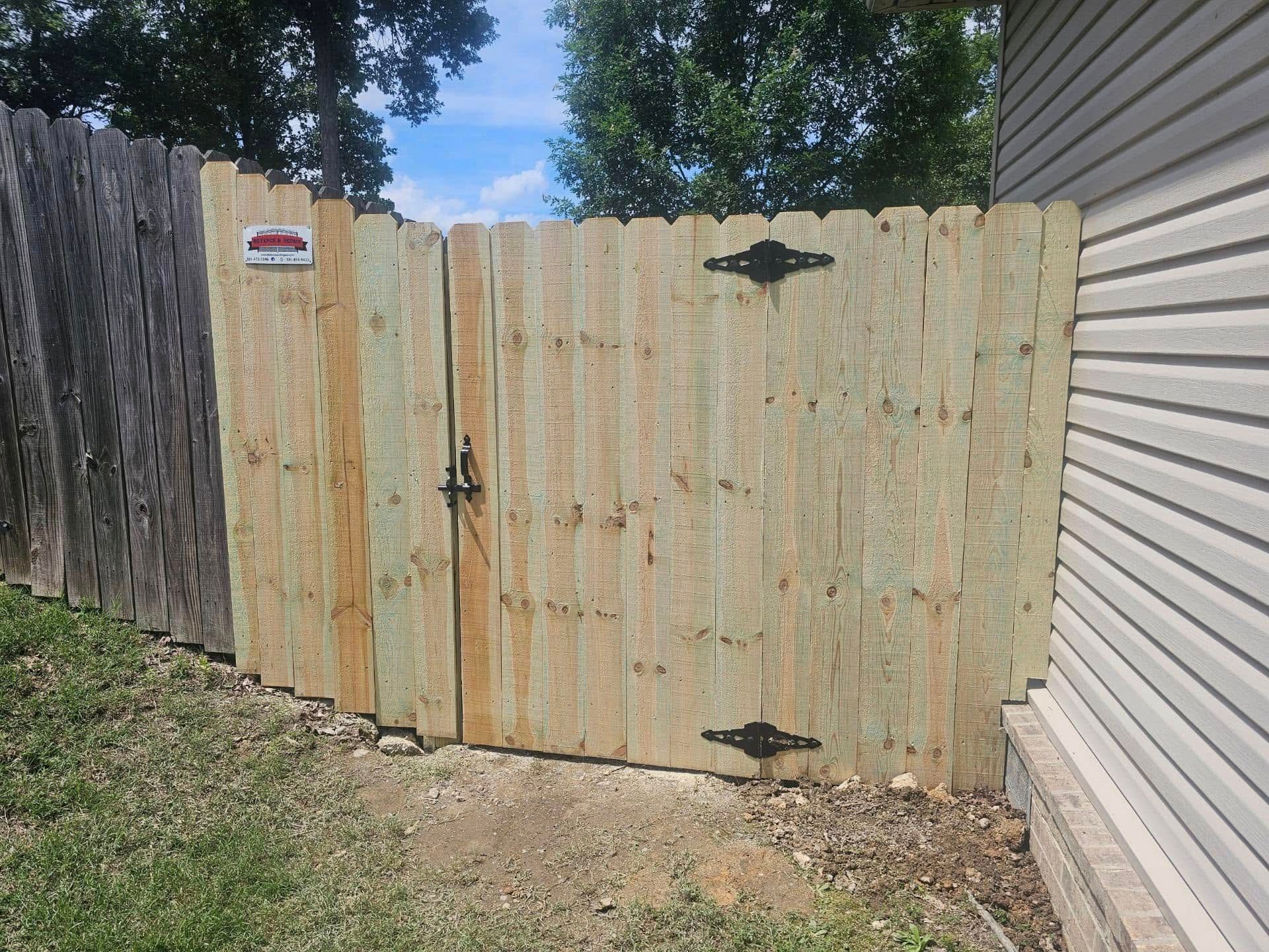 A wooden fence with a gate is next to a house.