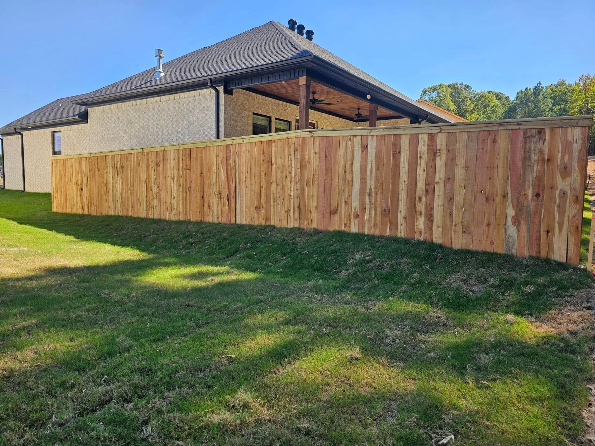 A wooden fence is in the backyard of a house.