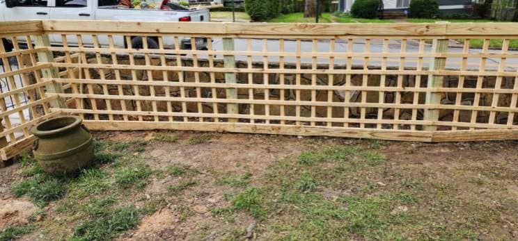 A wooden fence is sitting in the middle of a grassy field.