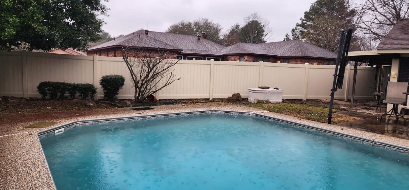 A large swimming pool in the backyard of a house with a white fence.