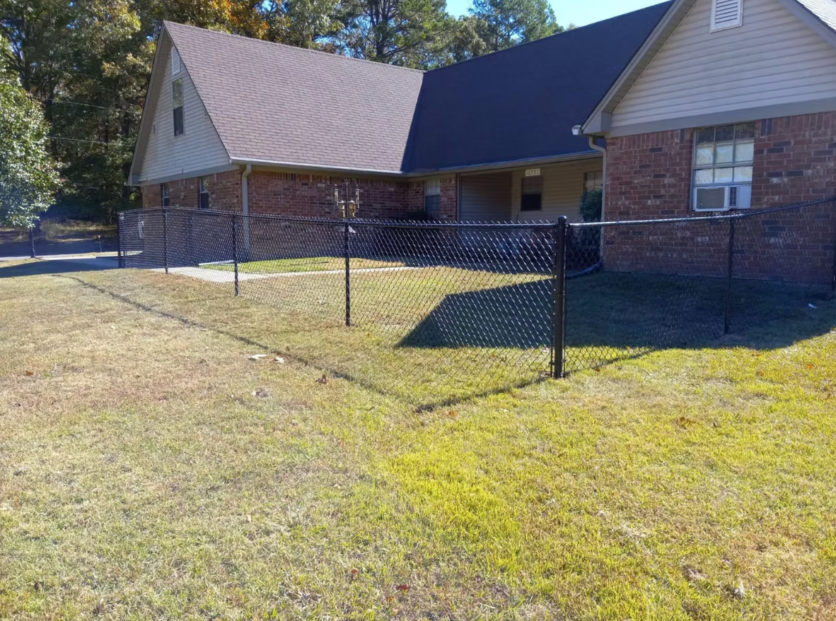 A brick house with a chain link fence in front of it.