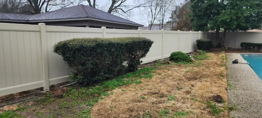 A white fence surrounds a swimming pool in a backyard.