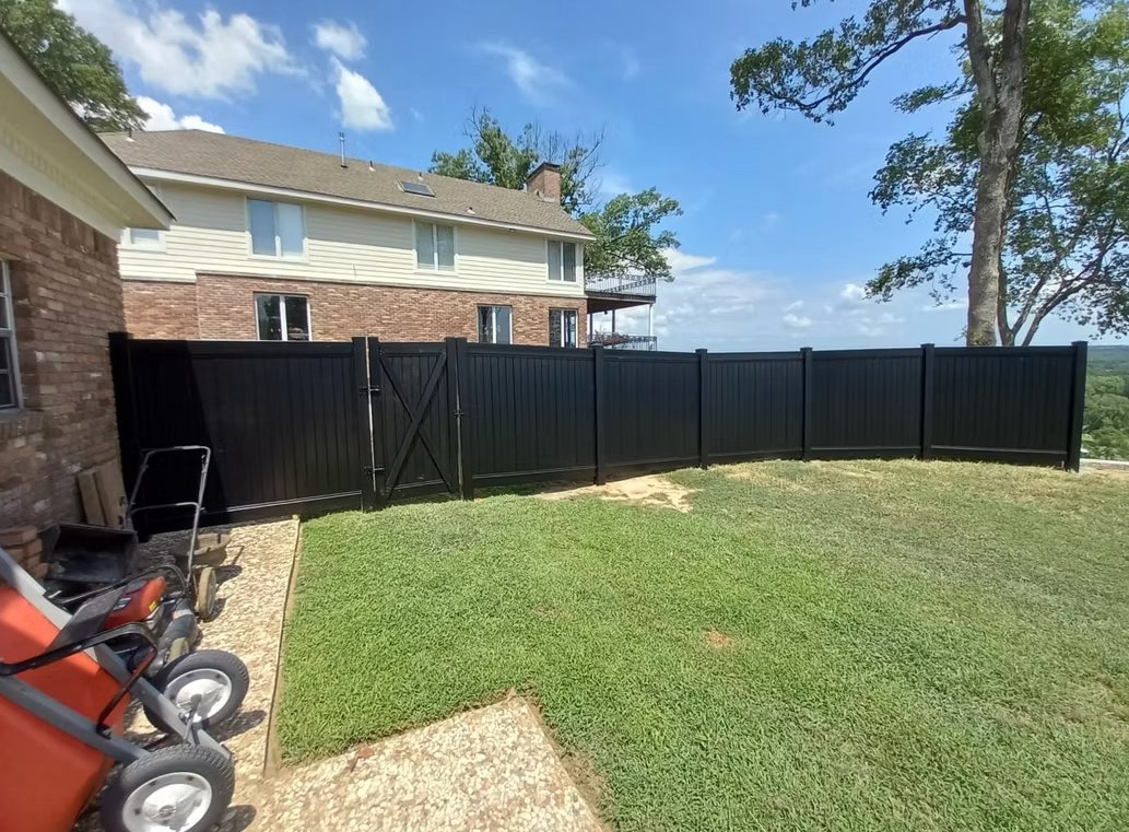 A black fence is in the backyard of a house.