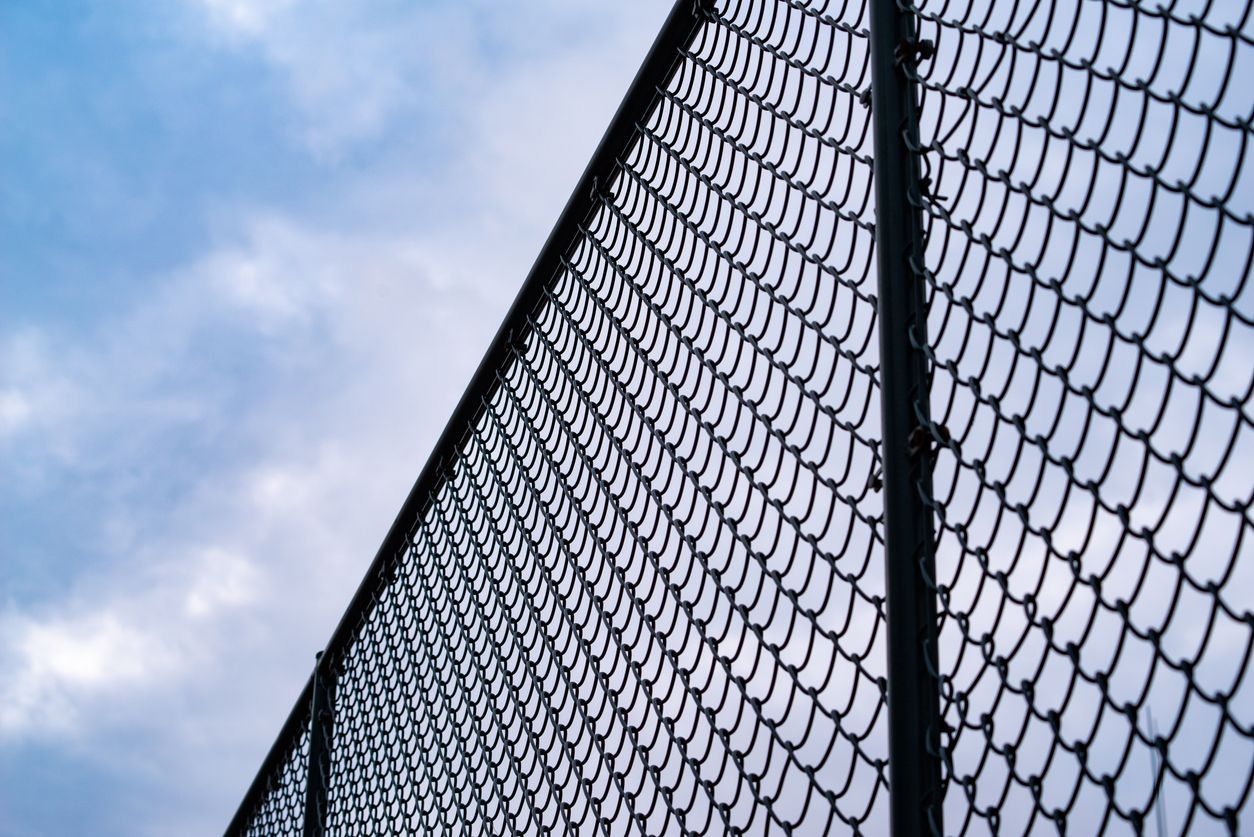 A chain link fence with a blue sky in the background.