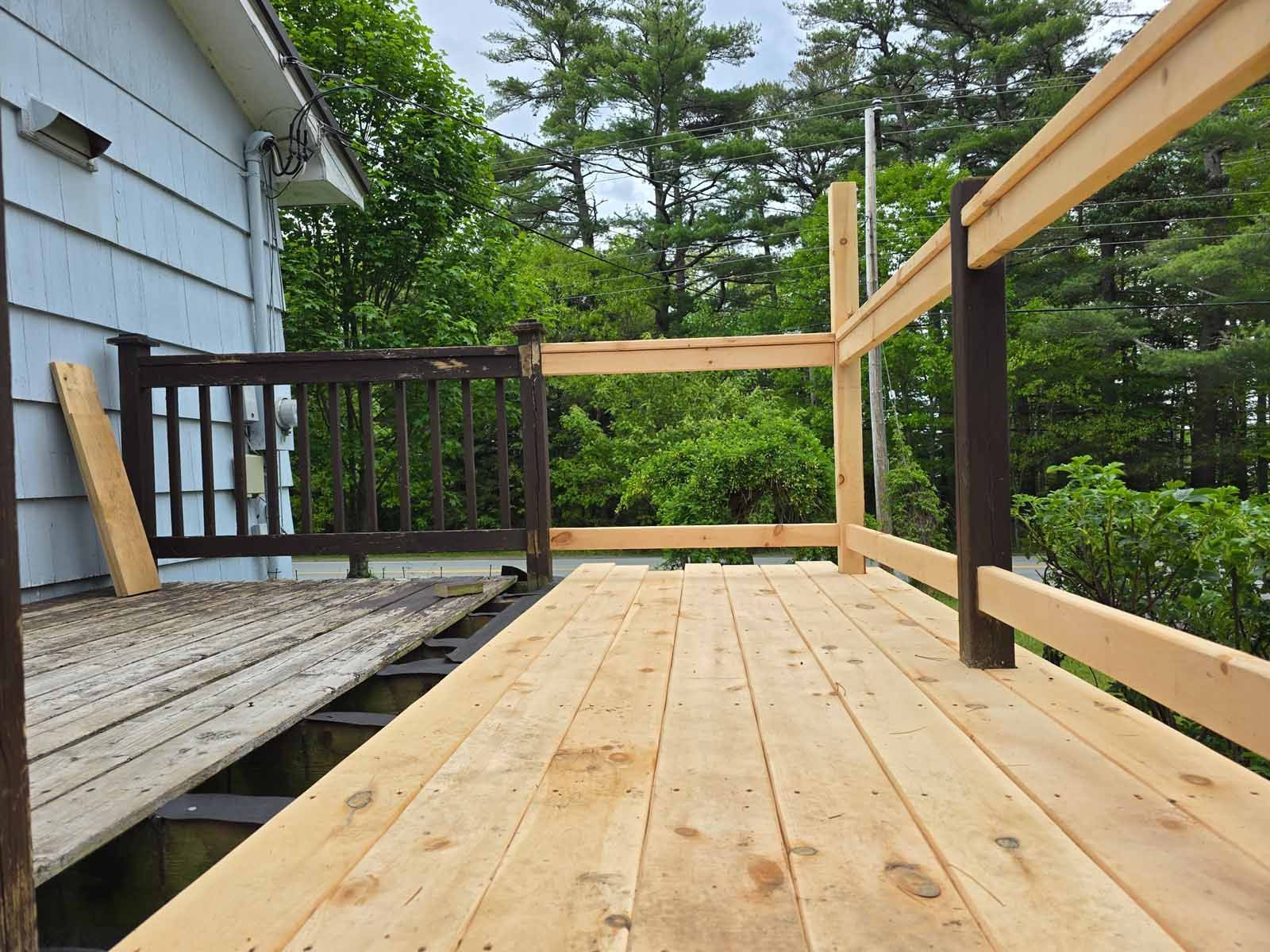 A wooden deck with a railing and a house in the background