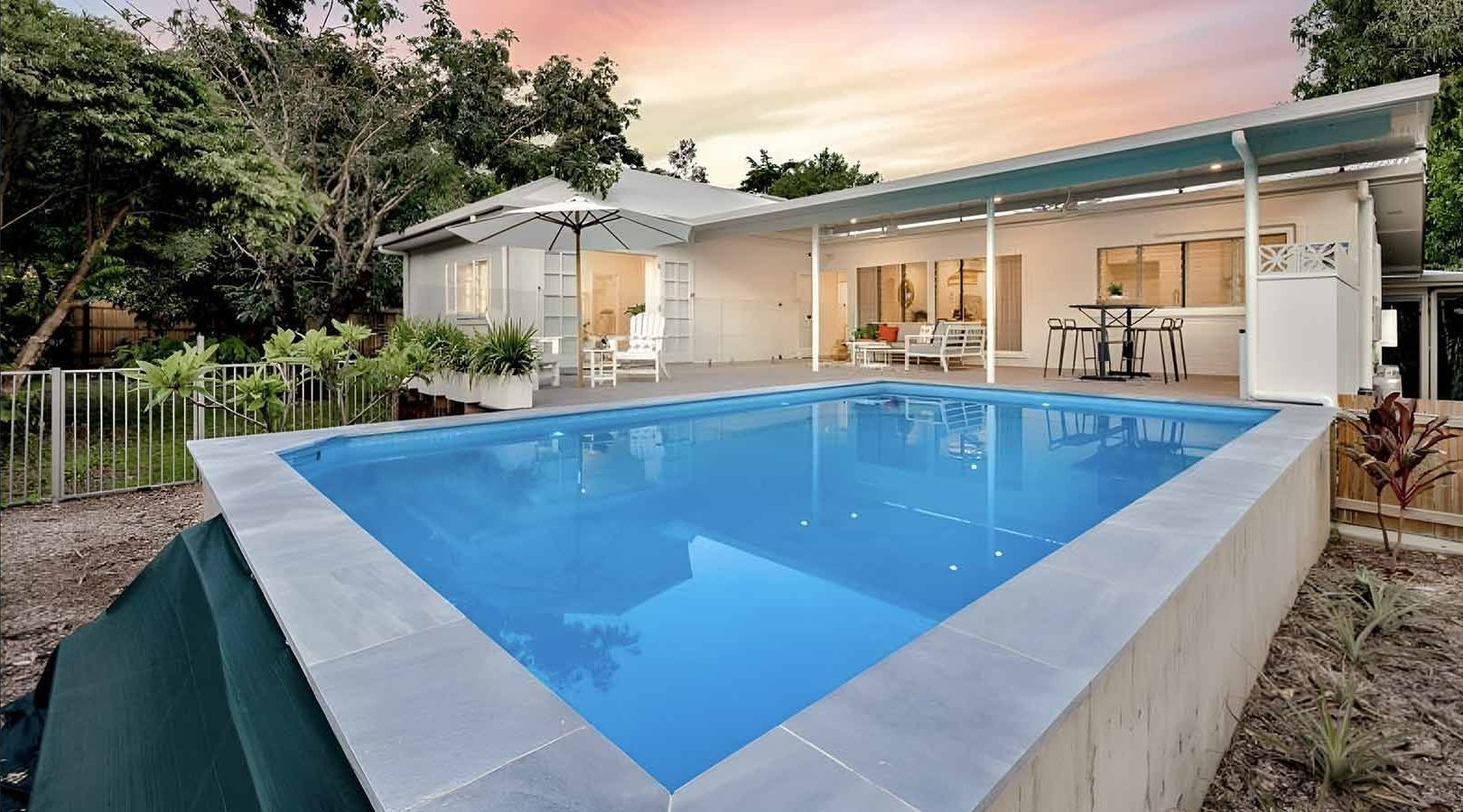 A Large Swimming Pool Is In Front Of A House — Pool Physicians NQ in Manoora, QLD