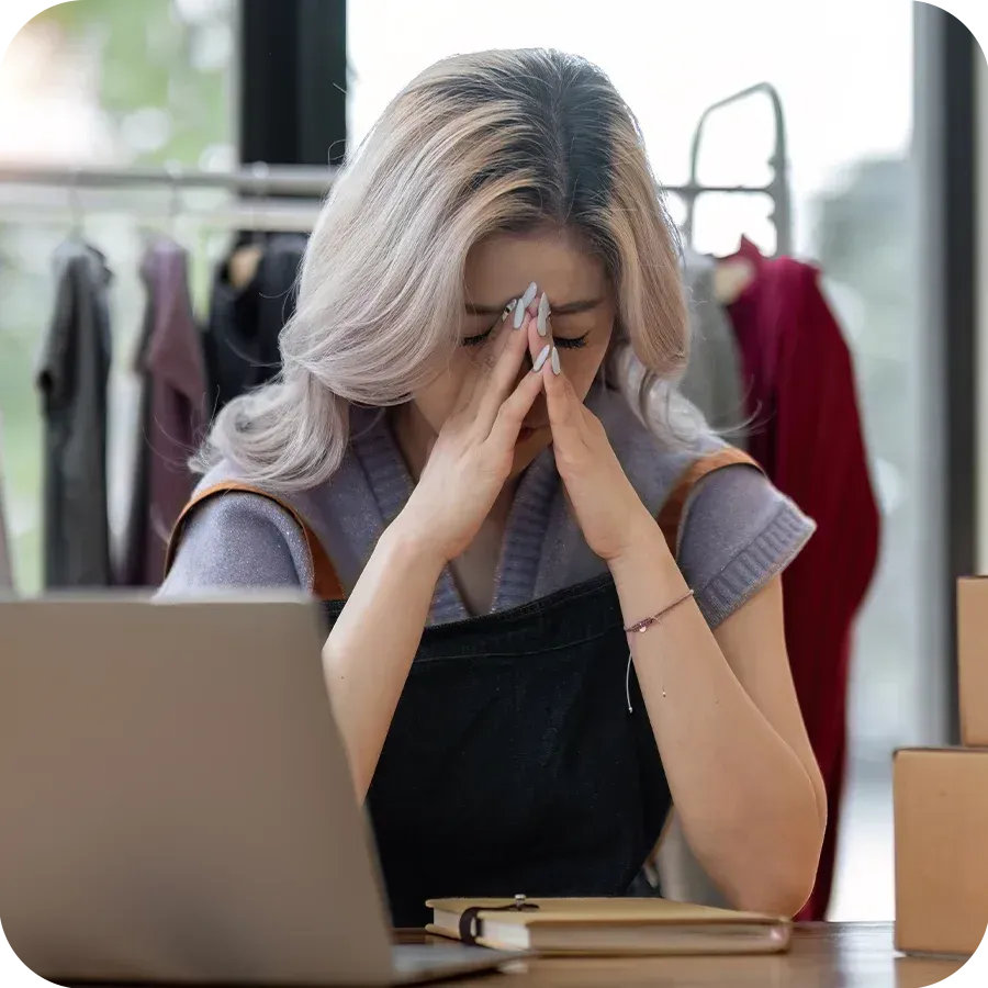 Frustrated business owner sat at her desk with her head in her hands