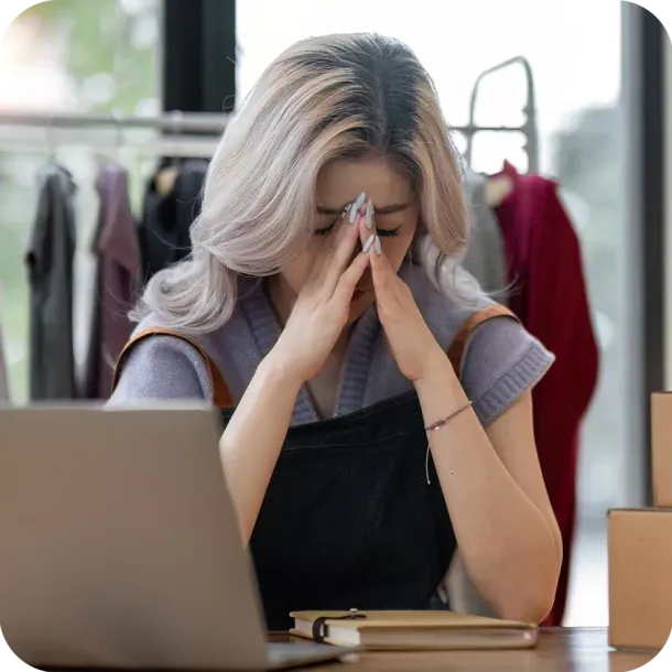 Frustrated business owner sat at her desk with her head in her hands