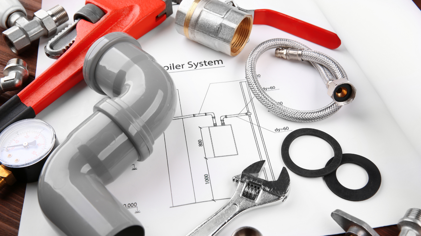 Plumbing tools and parts arranged on a blueprint, including pipes, a wrench, and fittings.