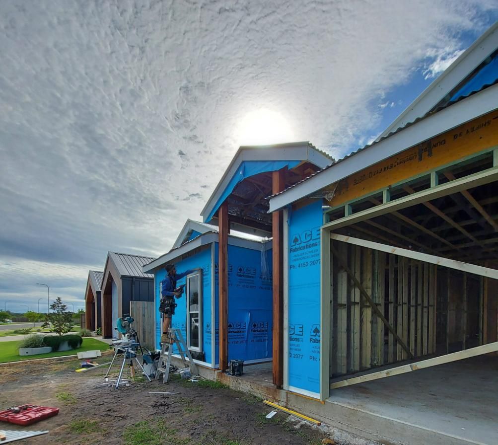 A Man Is Standing on A Ladder in A Building Under Construction — Formosa Building And Renovations in South Kolan, QLD