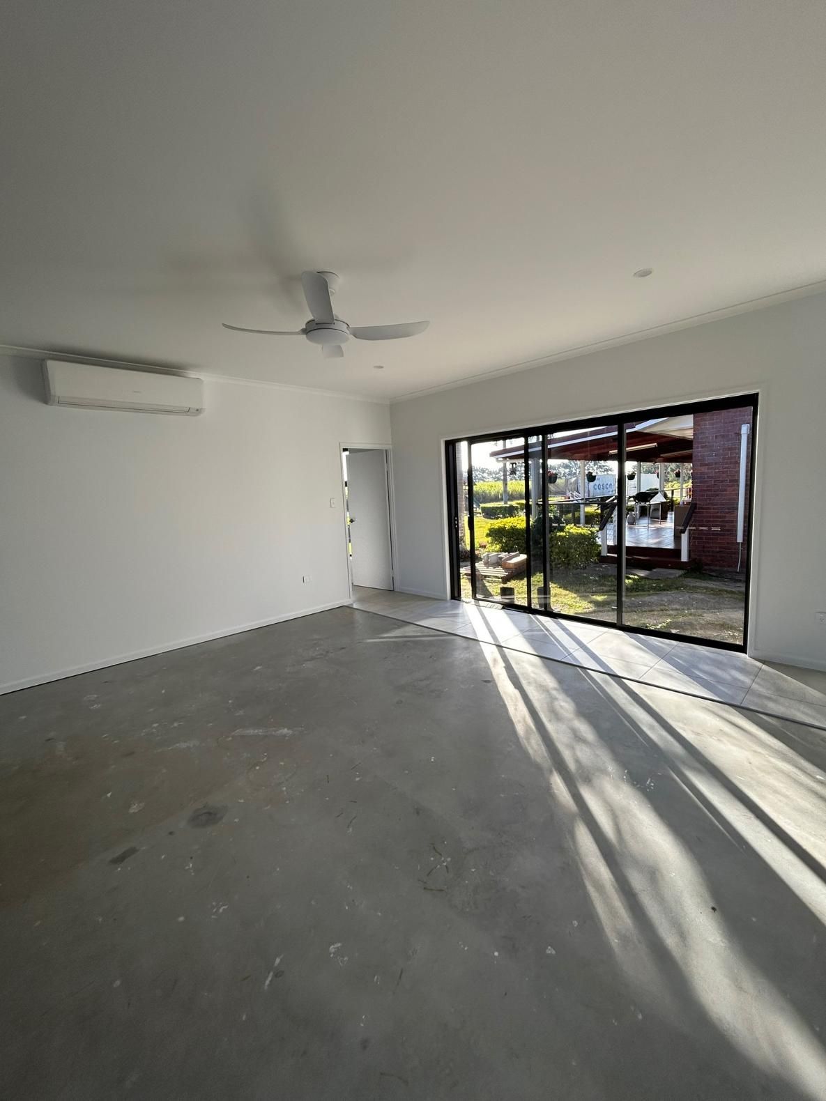 A Large Empty Room with A Ceiling Fan and Sliding Glass Doors — Formosa Building And Renovations in Bargara, QLD