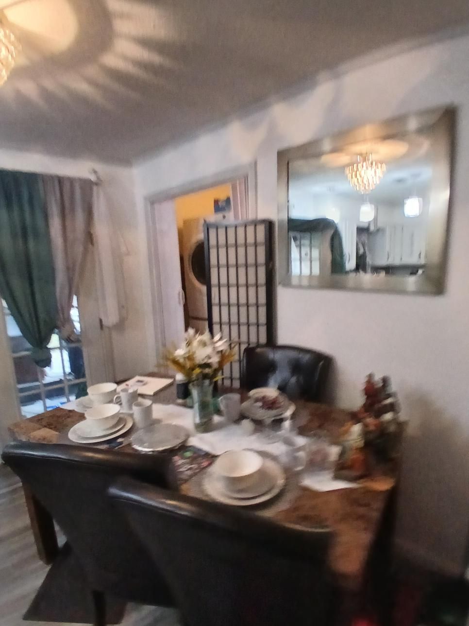 Dining room with table set for a meal; mirror and closed screen in the background.