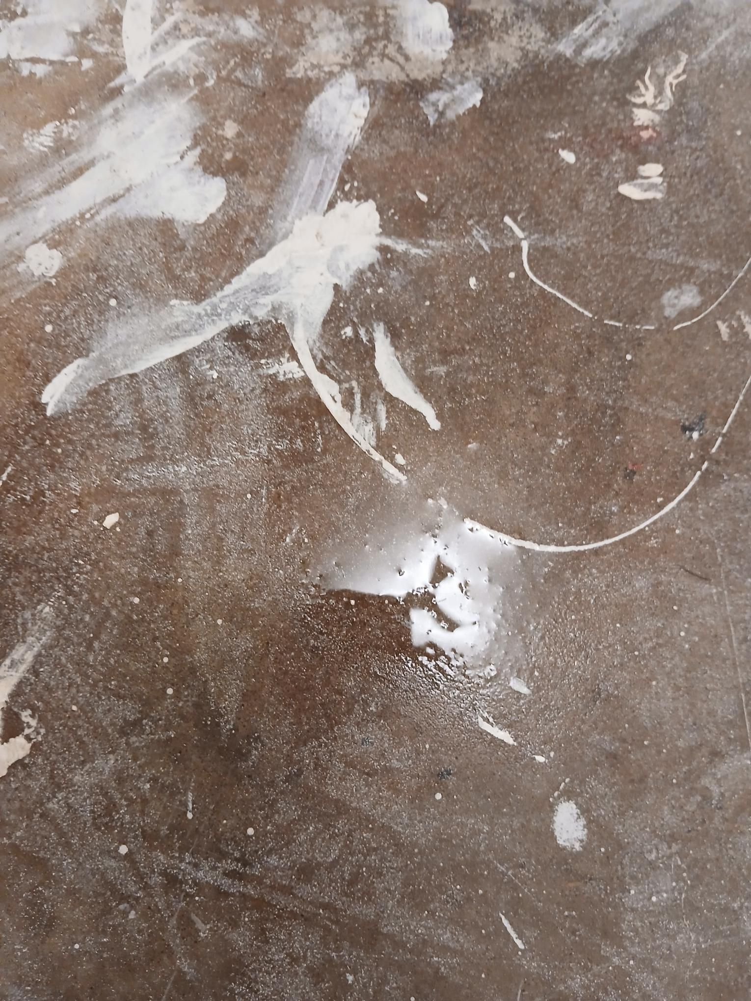 Brown floor splattered with white paint.