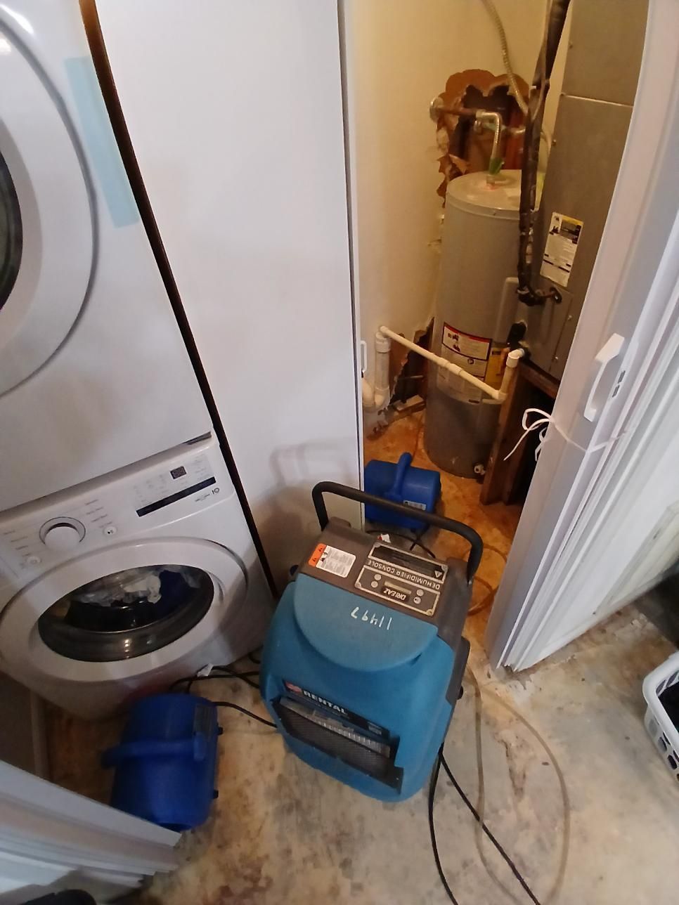 Washing machine, water heater, and dehumidifier in a utility closet. A stacked washer-dryer is on the left.