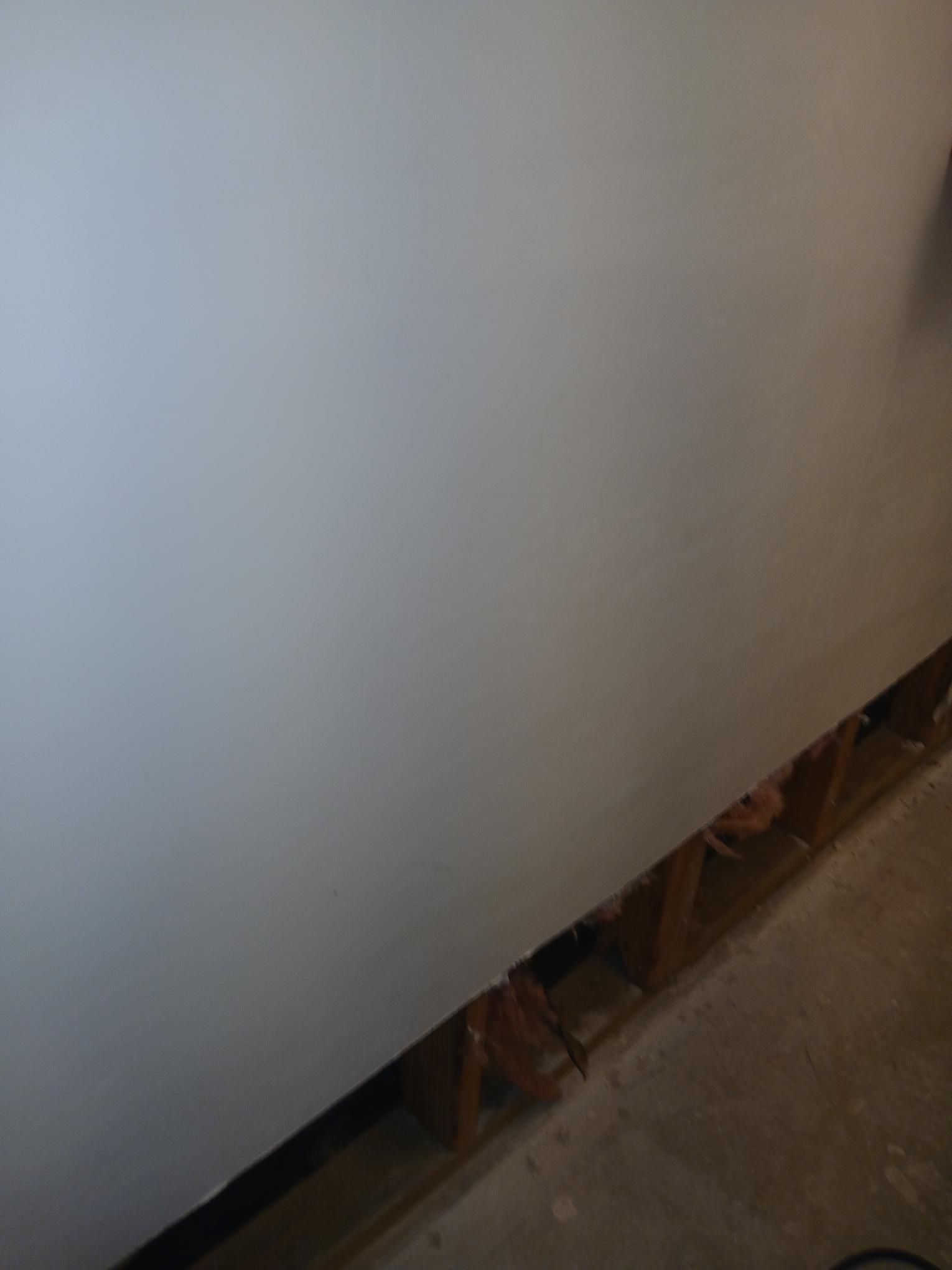 White wall and exposed wood framing meet a concrete floor.