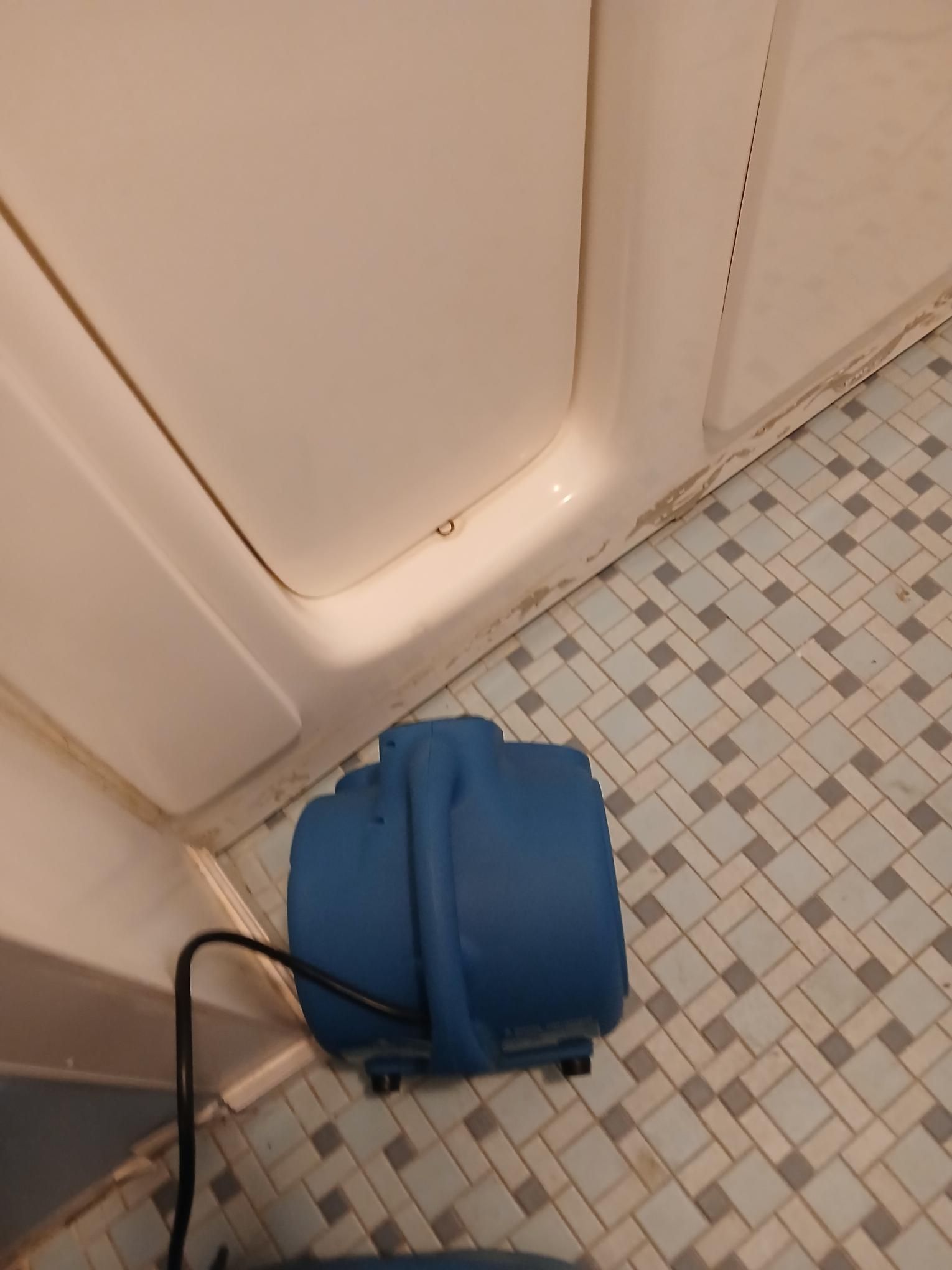 Blue blower in a shower, drying floor tiles and walls after a leak or flood.