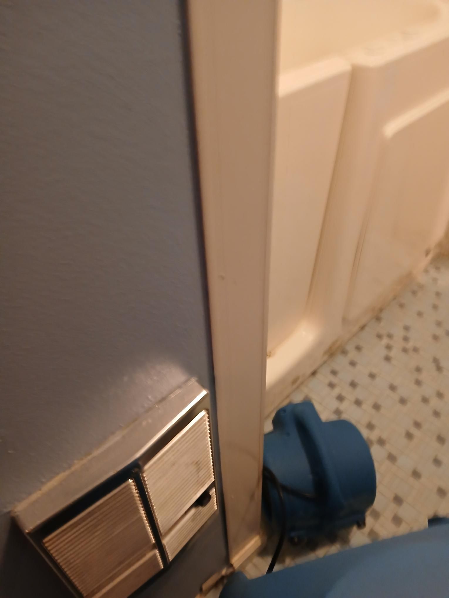 Blue wall, off-white door frame, and cabinet.  Blue blower on floor,  light blue and white speckled floor.