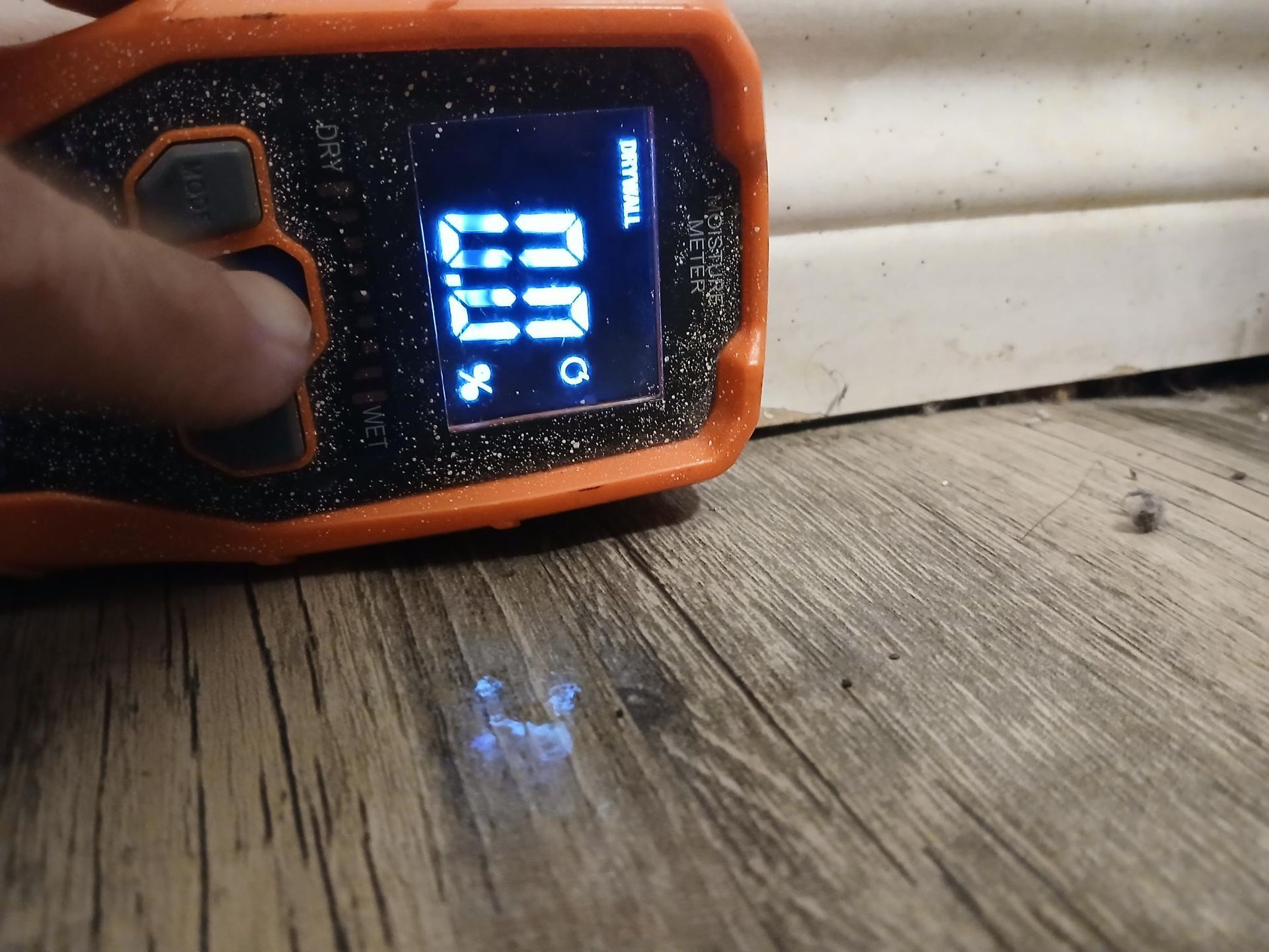 Person's finger pressing a button on an orange device. Screen displays 
