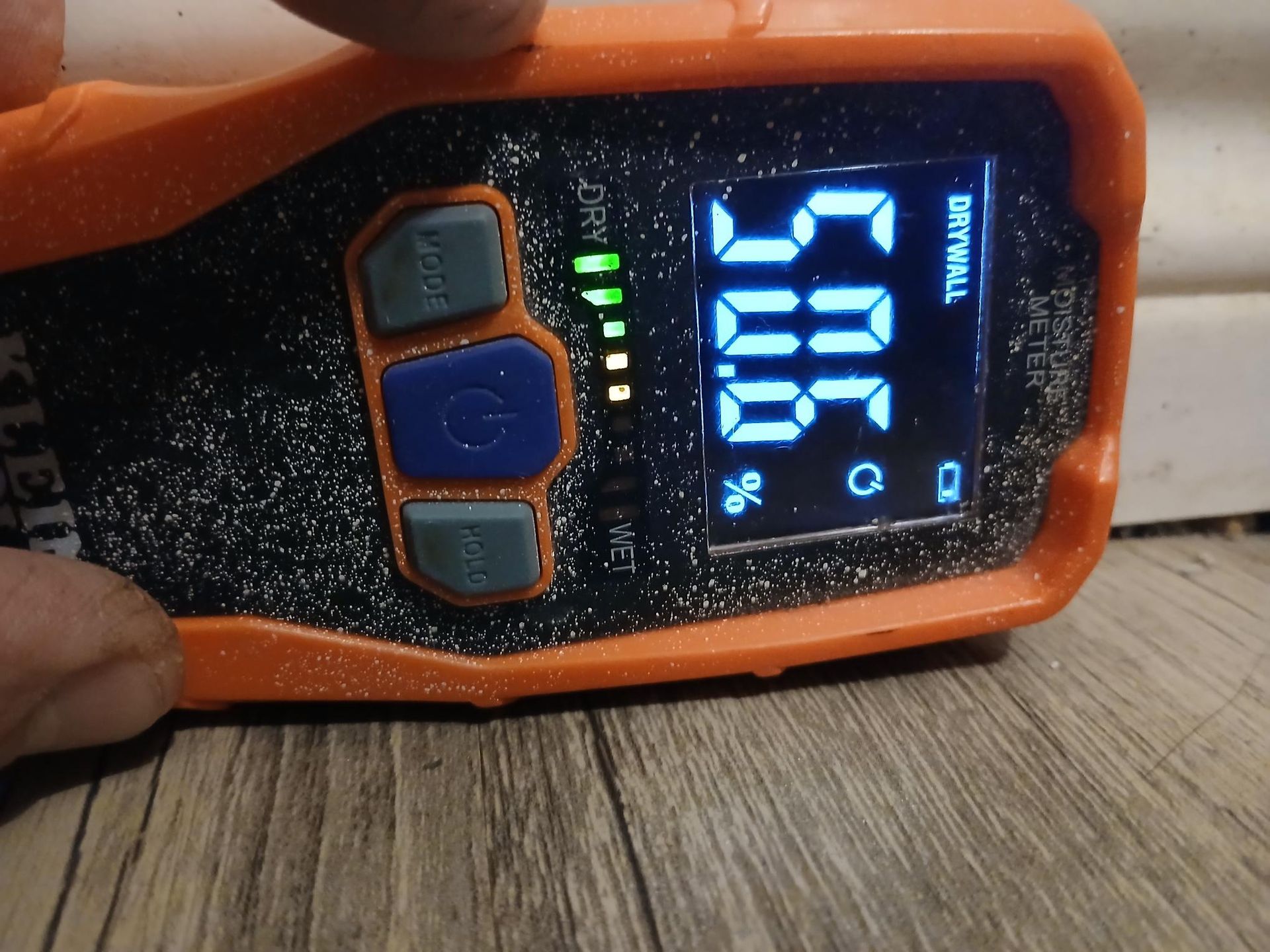Orange moisture meter displaying a reading of 30.6% on drywall.