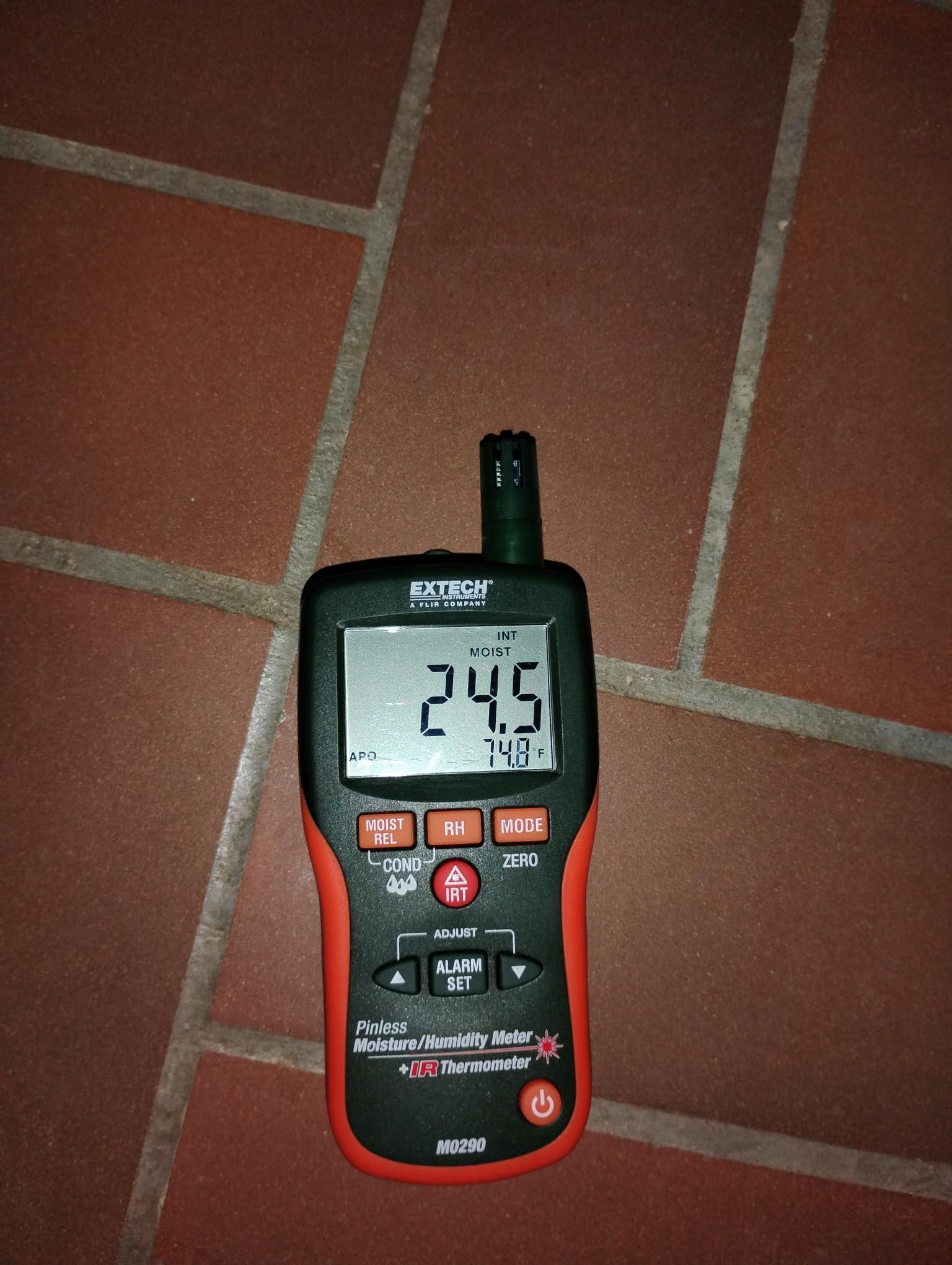 A black and red digital meter displaying 24.5 on a brick floor.