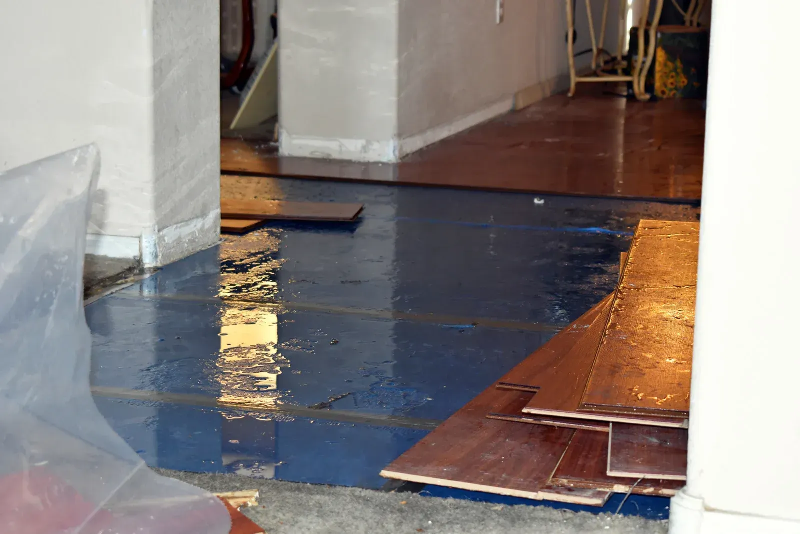Flooded interior space; blue flooring, wet wooden planks, white walls.
