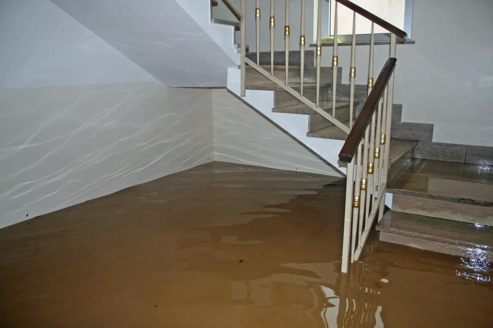 Basement flooded with muddy water, stairs on the right.