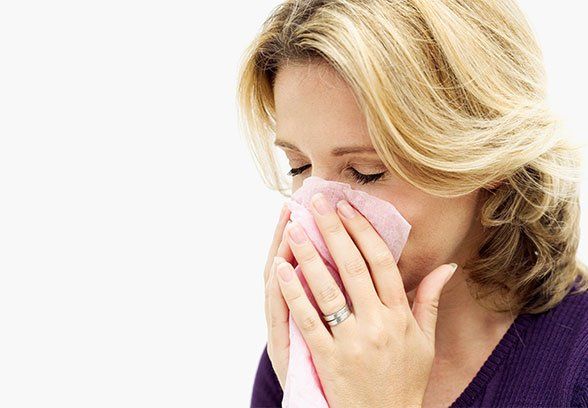A person sneezing into a tissue