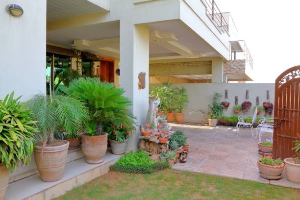Three buckets of paint and brushes are sitting on a white towel in an empty room.