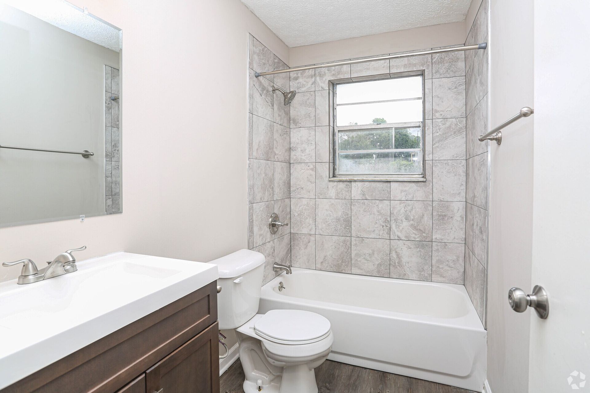 A bathroom with a toilet , sink , tub and mirror.