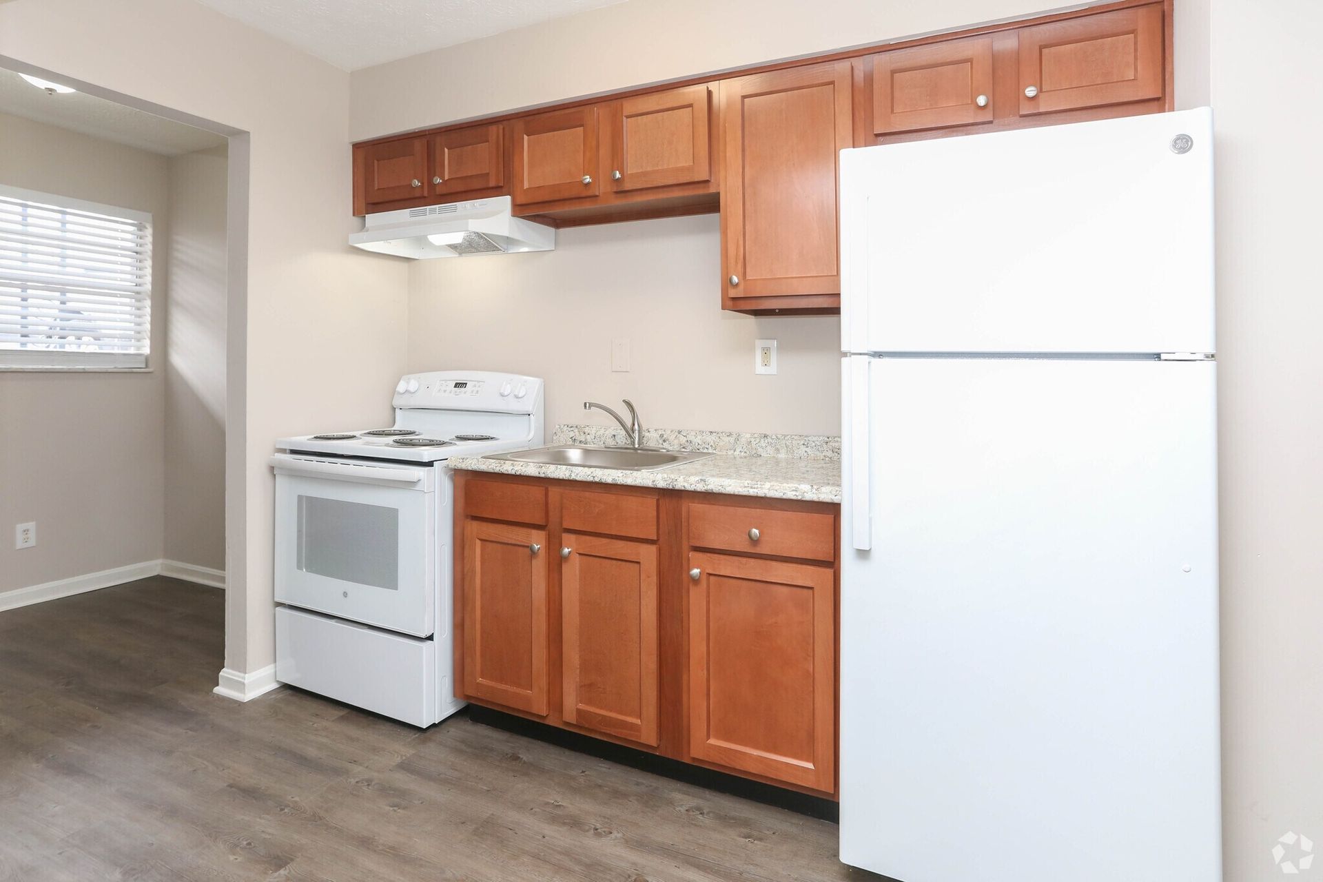 A kitchen with a stove , refrigerator , sink and cabinets.