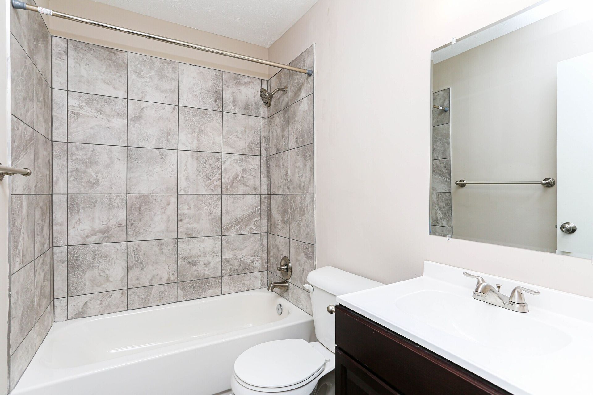 A bathroom with a tub , toilet , sink and mirror.