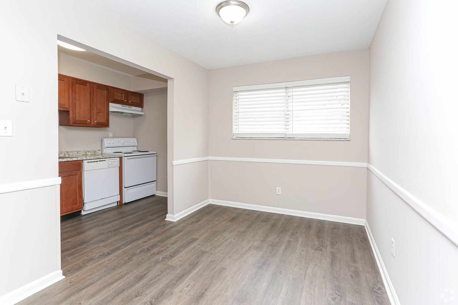 A living room with hardwood floors and a kitchen in the background.