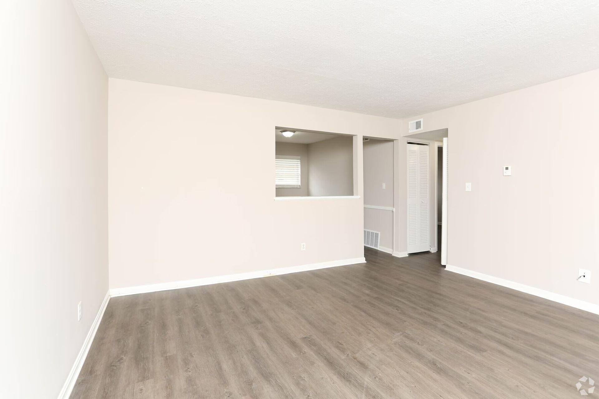 An empty living room with hardwood floors and white walls.