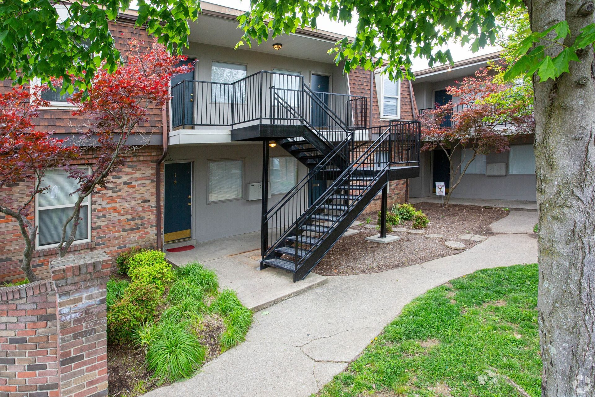 A brick apartment building with stairs leading up to the second floor.