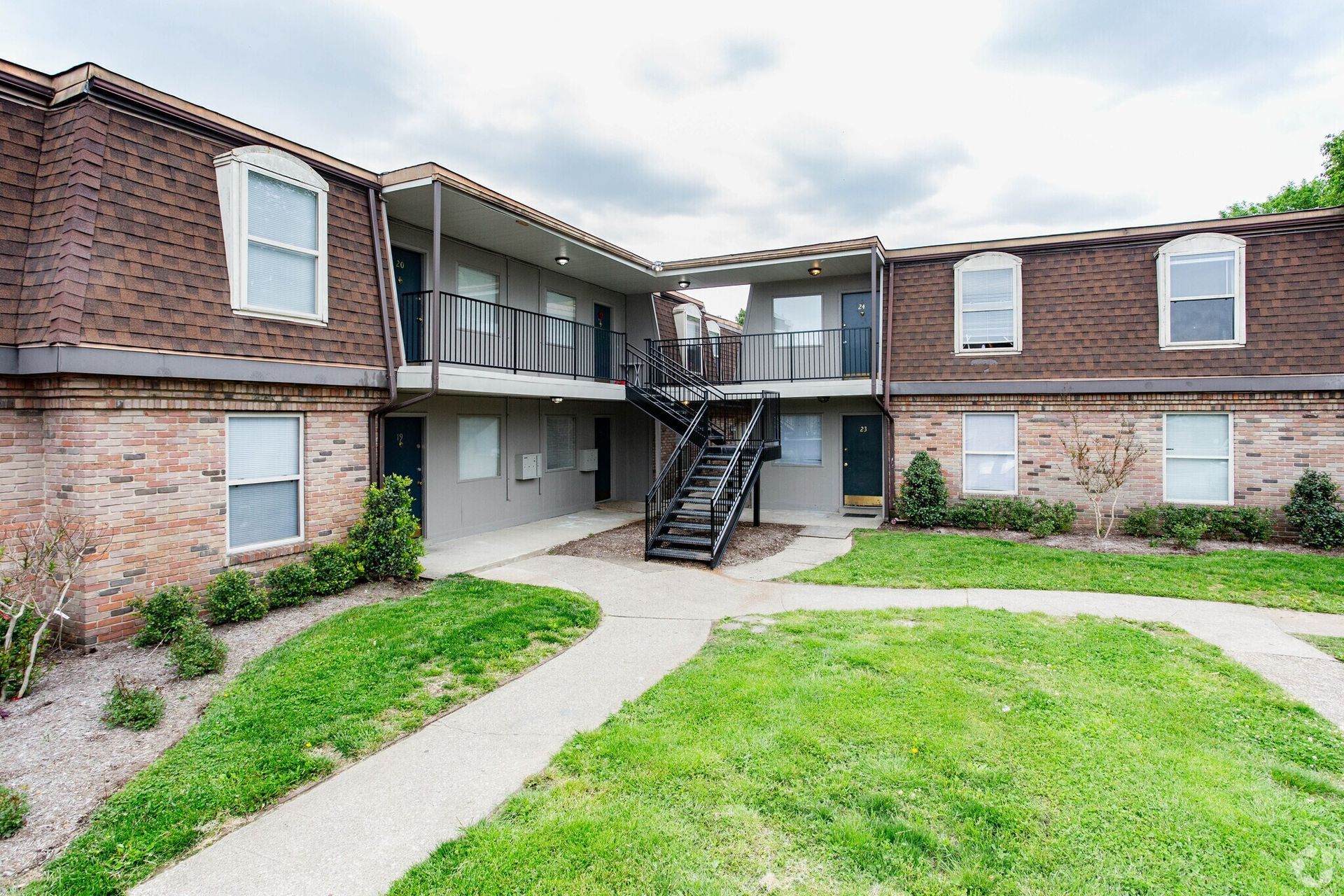 A large brick apartment building with stairs leading up to the second floor.