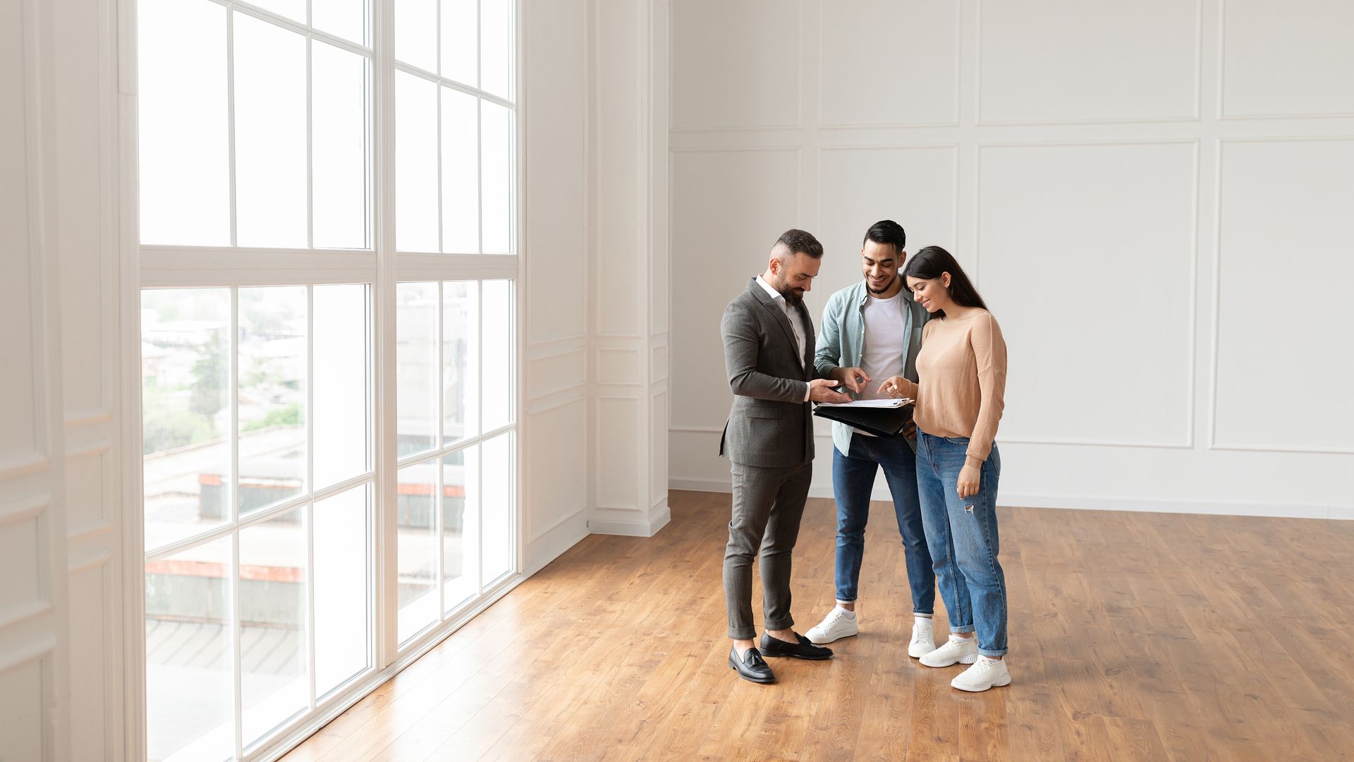 A man is standing next to a woman and a man in an empty room.