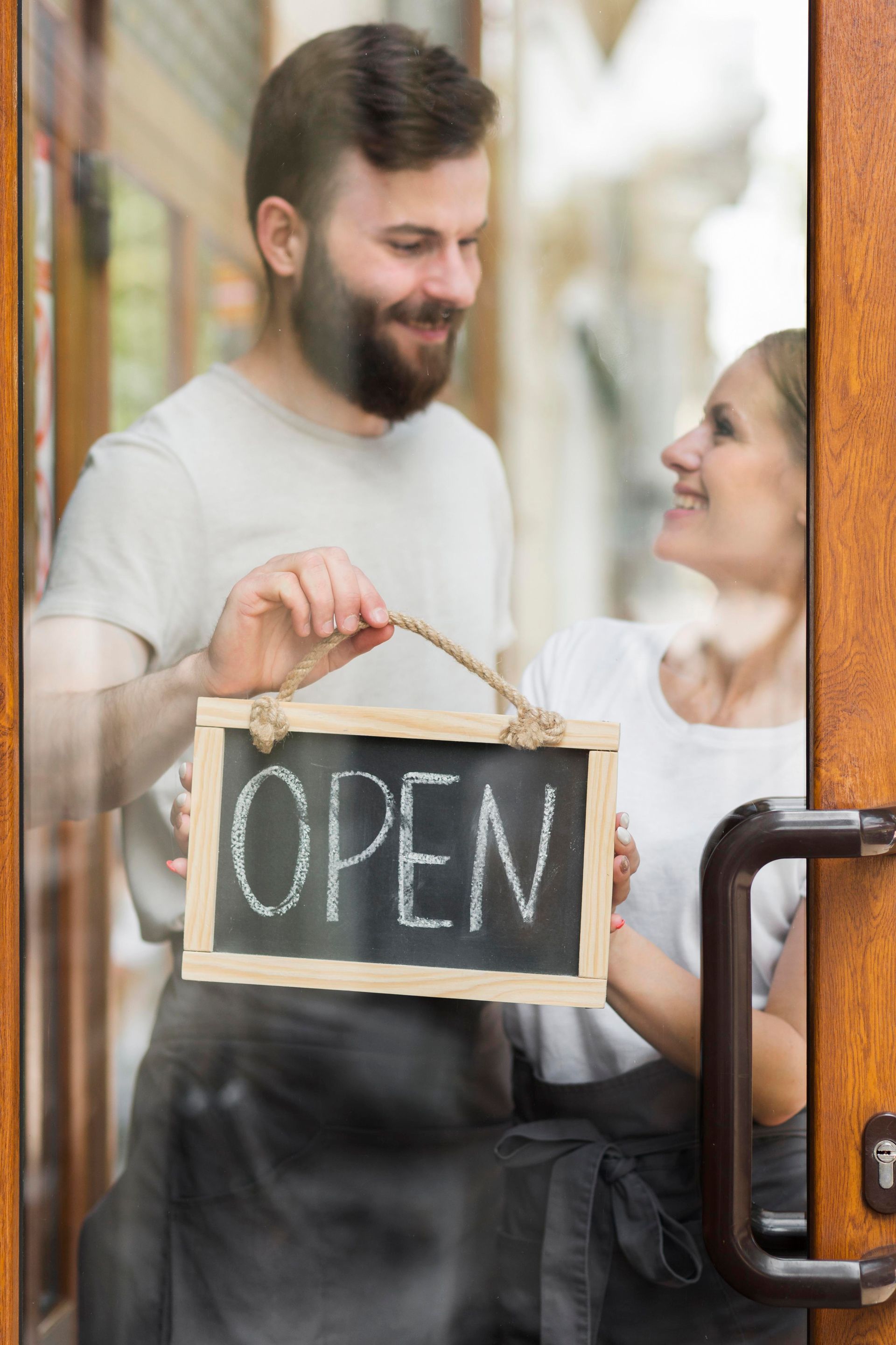 Man and woman opening a shop, holding an 
