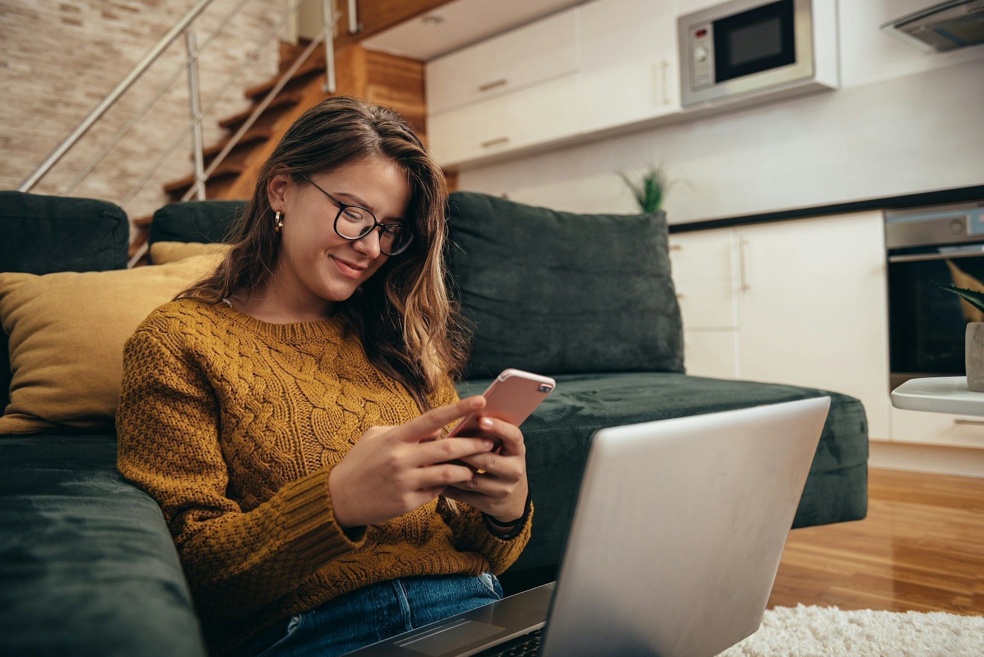 A woman is holding a cup of coffee and looking at her cell phone.