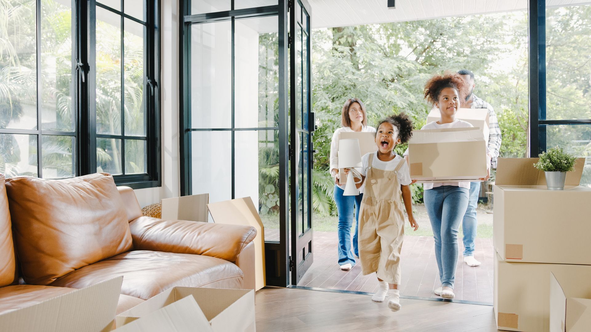 A family is moving into a new home carrying boxes.