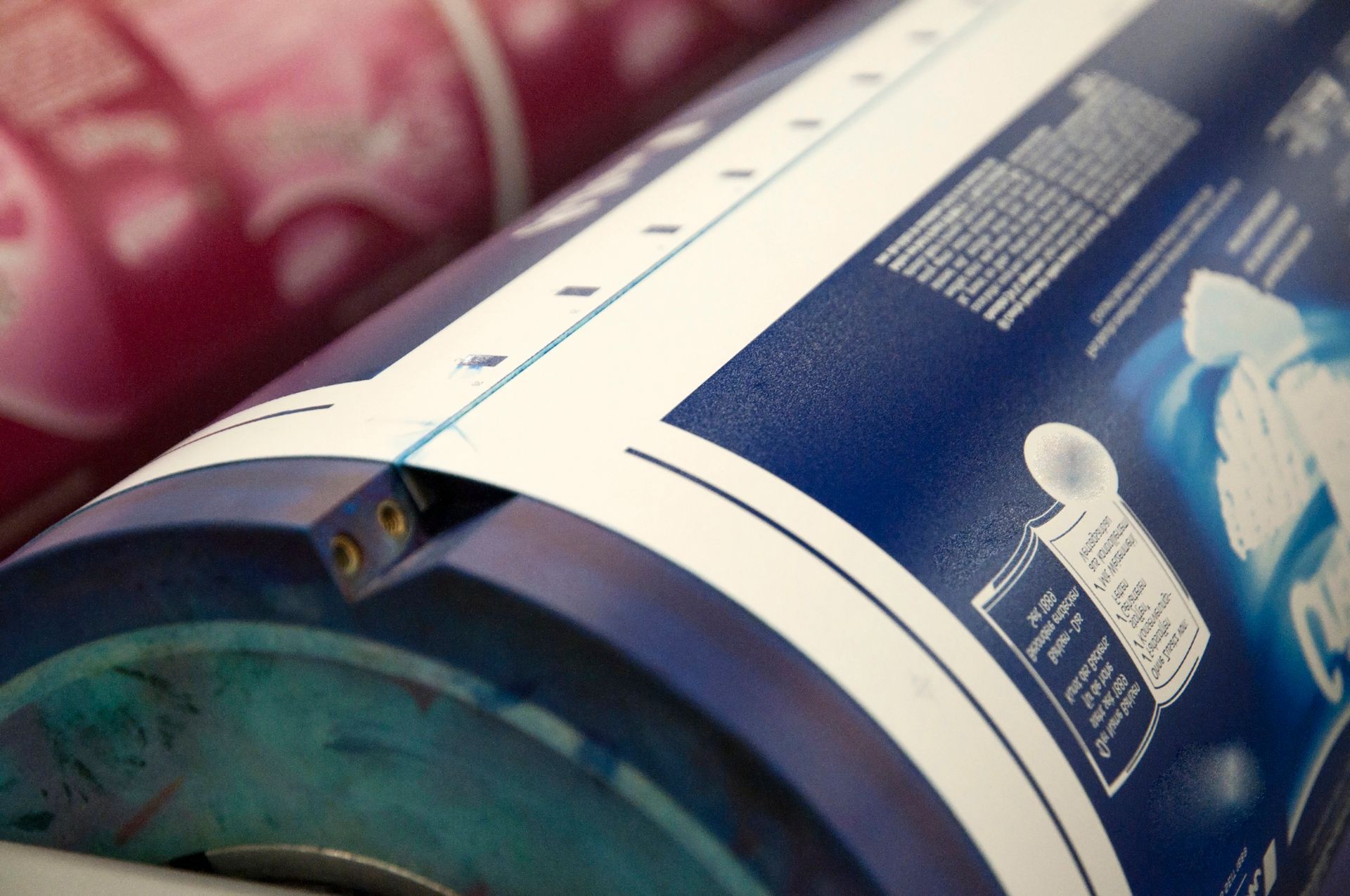 Primo piano di un cilindro di stampa blu con testo e linee bianche, parte di una macchina da stampa.