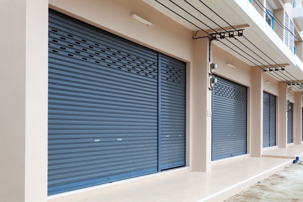 Gray Metal Roll-up Shop Doors on a Building With a Beige Facade — Duncan's Doors In Dalby, QLD