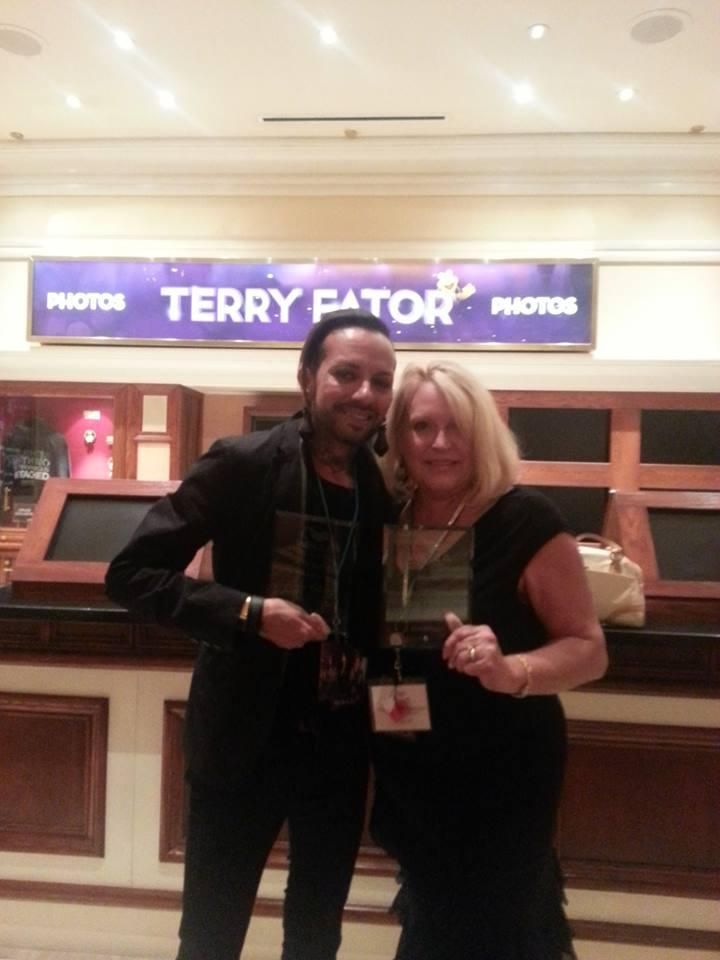Two people posing together in front of a Terry Fator sign at a venue