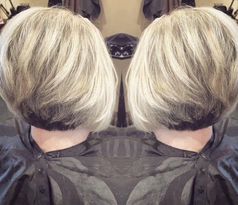 Side-by-side mirrored view of a blonde bob haircut from the back, showing layered silver-blonde hair.