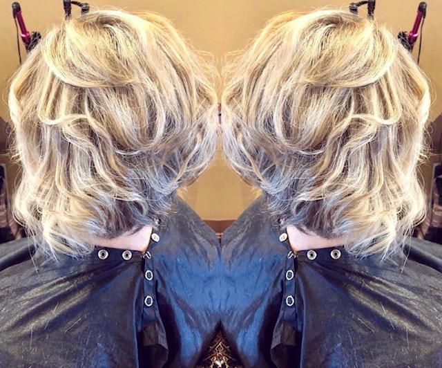 Side-by-side back view of short blonde tousled hair with dark clips on a salon cape