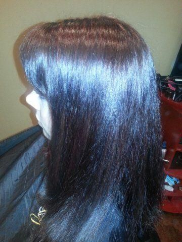 Side view of long, straight dark brown hair with a glossy shine against a plain background