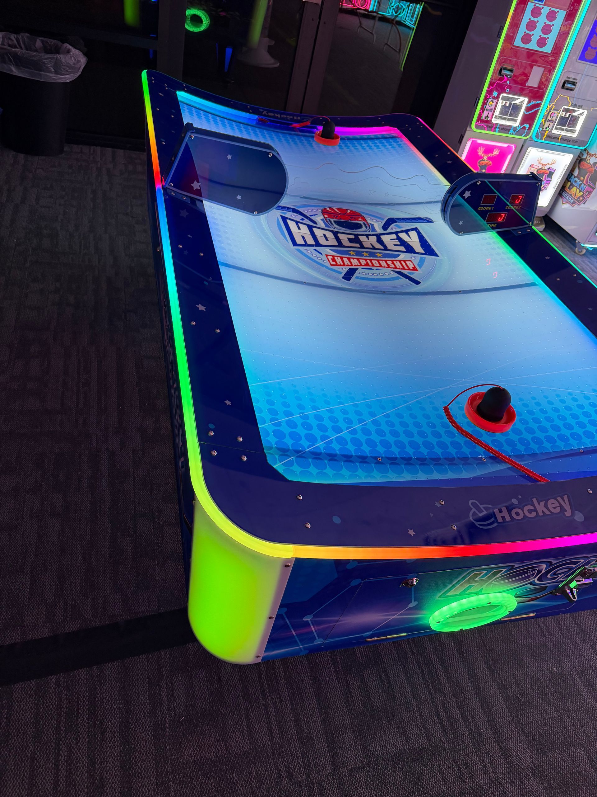 Neon-lit arcade air hockey table with lit edges and a puck on the surface